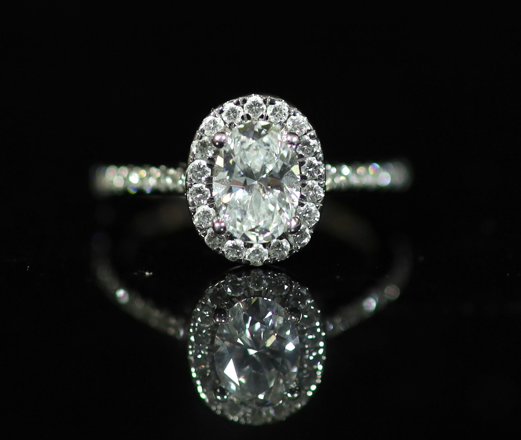 A Rox platinum and oval cut single stone diamond ring, with diamond set border and diamond set shoulders